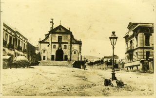 Fotografia antiga color sèpia de la plaça Lesseps amb l'esglèssia al fons