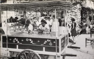 Fotografia antiga en blanc i negre d'una parada ambulant de gelats amb els venedors