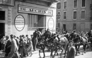 Fotografia antiga en blanc i negre d'una processó amb caballs