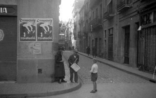 Fotografia antiga en blanc i negre d'un home comprant un diari al carrer