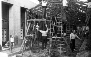 Fotografia antiga en blanc i negre d'uns homes engalanant un carrer amb garlandes