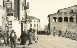 Fotografia antiga d'un carrer de Gràcia amb gent caminant