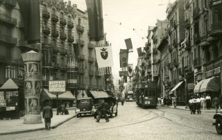 Fotografia antiga en blanc i negre del carrer Gran de Gràcia en plena activitat diària